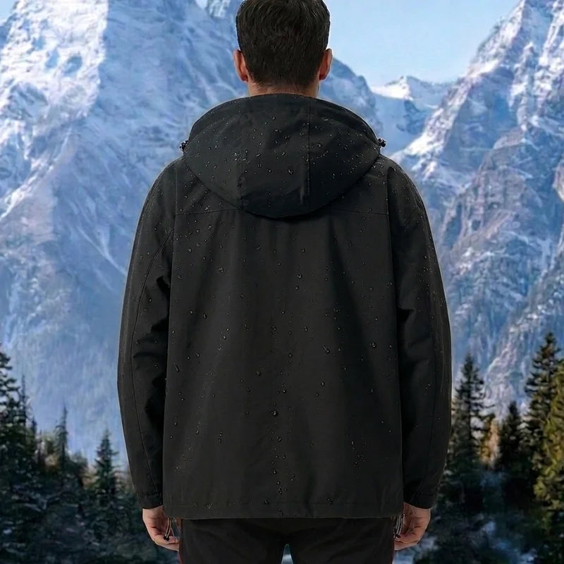 Vue dos veste noire — capuche, gouttes d'eau perlantes, fond montagne enneigée et forêt de pins
