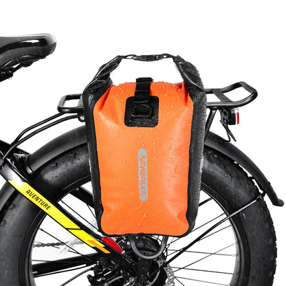 Gros plan sur une sacoche orange montée sur porte-bagage arrière, gouttes de pluie visibles, crochets noirs apparents