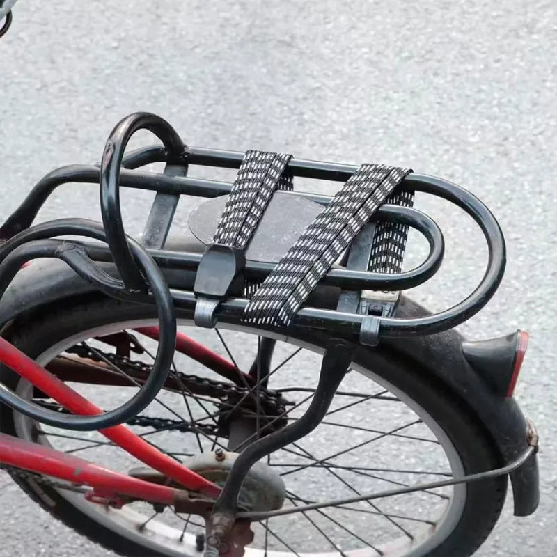 Photo réelle du sandow replié sur porte-bagage de vélo rouge — crochets accrochés sur les tubes