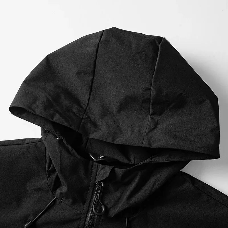 Macro capuche veste noire posée sur fond blanc — structure volumineuse, cordon de réglage