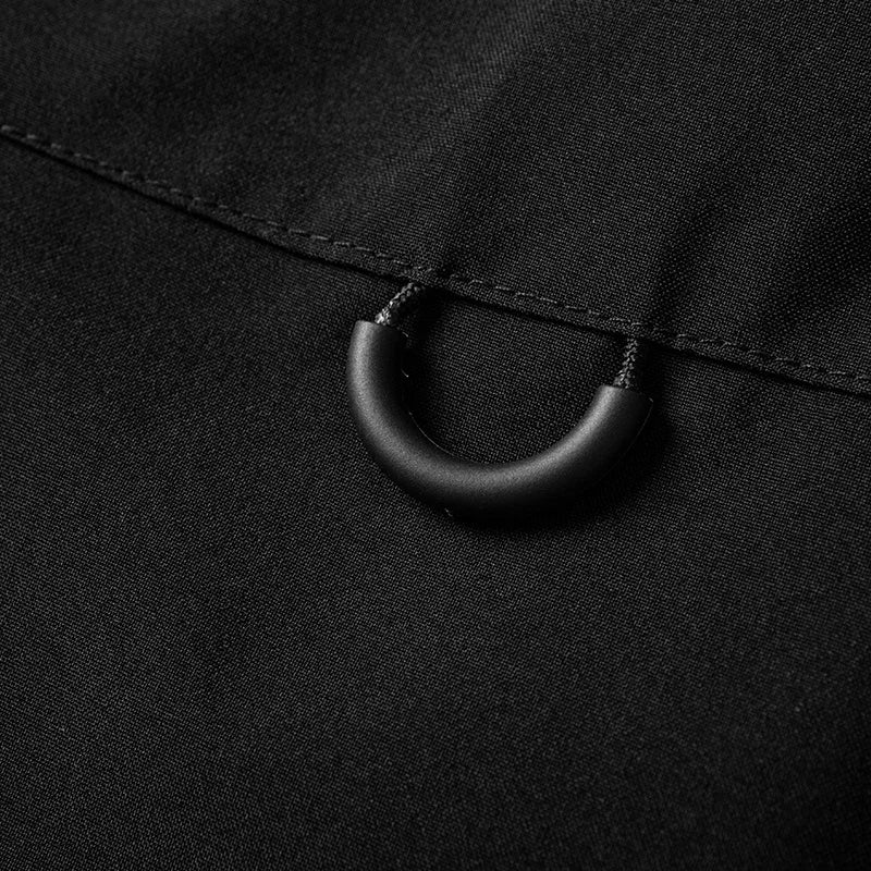 Macro anneau en D sur poche poitrine veste noire — détail accroche clé ou accessoire
