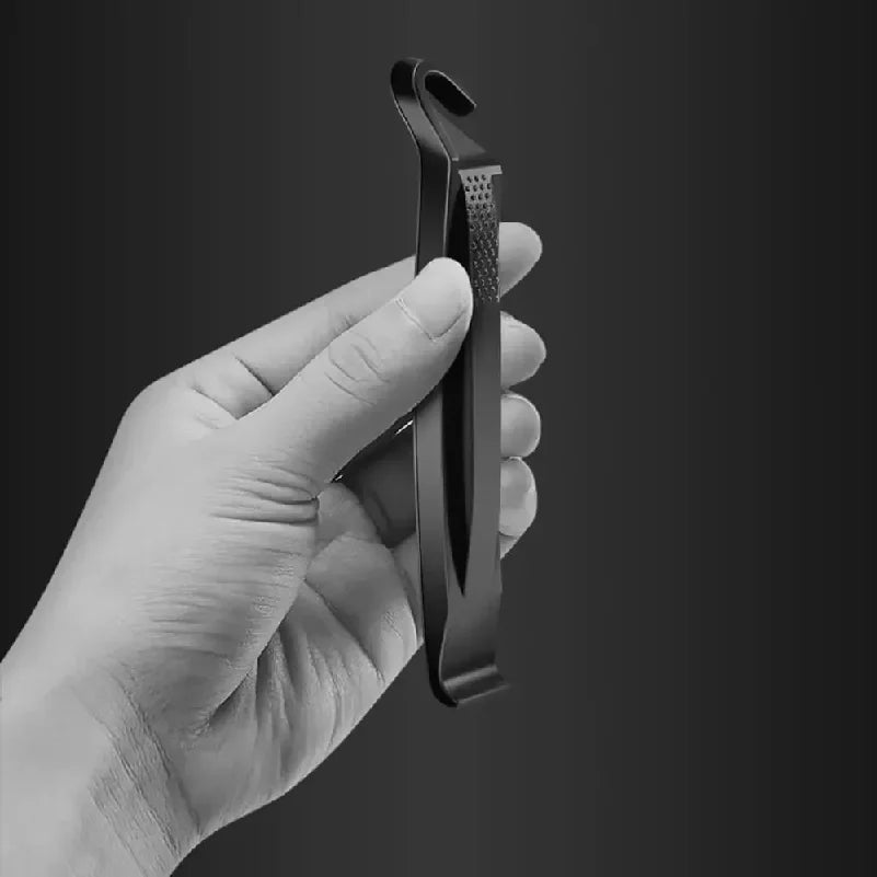 Un démonte-pneus noir tenu dans la paume d'une main, photo N&B fond sombre